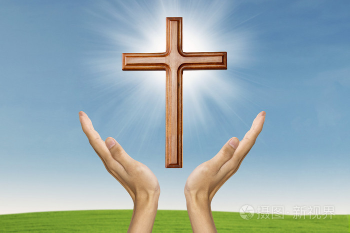 男性与一个木制的十字架祈祷的手