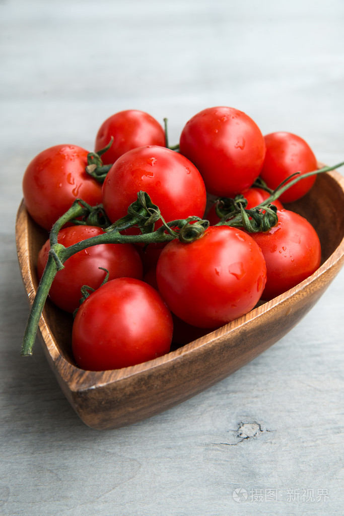 新鲜美味西红柿红色的心形状上的木制板