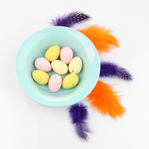 碗和装饰羽毛上白色孤立的复活节彩蛋