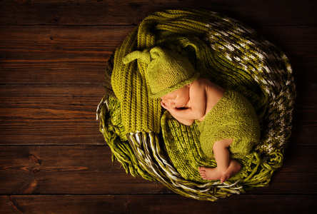 婴儿新生儿的画像，孩子睡在羊毛帽子棕色木制背景