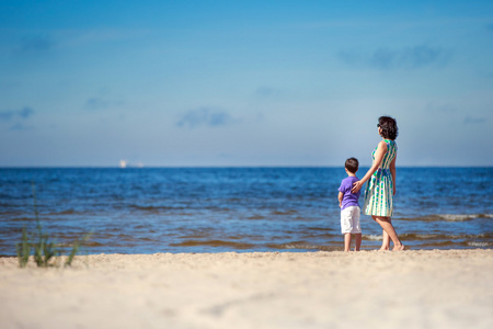 后视图的母亲和她的儿子在夏日海滩