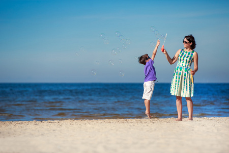 母亲和儿子在地处热带的海滩享受时间