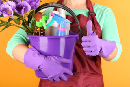 家庭主妇拿着水桶与清洗设备在彩色背景上。春季大扫除的概念照片
