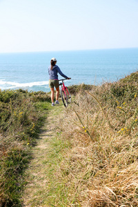 由海洋海岸线的女孩骑着自行车