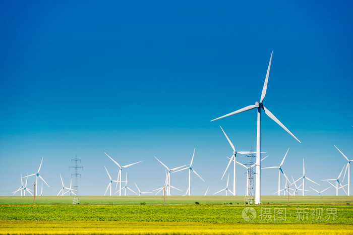生成与蓝色的天空和绿色草地上的风力发电的风车