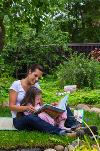 母亲和女儿读本书在户外