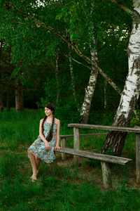 漂亮的女孩坐在木凳上森林里