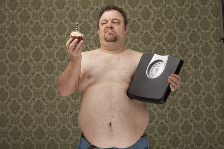 超重男性持有规模和杯形蛋糕
