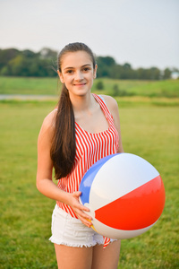 快乐的年轻女子，捧着一个彩色的充气大球
