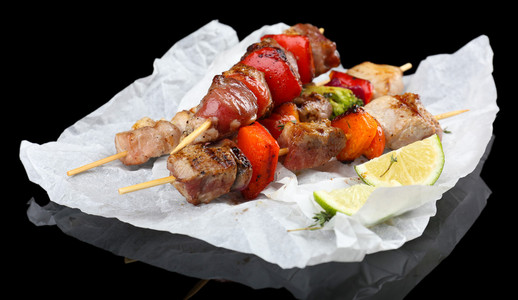 在黑色背景上的猪肉烤串照片