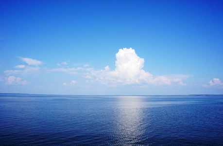 蓬松的表面与涟漪和蓬松的云彩的天空清澈碧蓝的海水表面照片