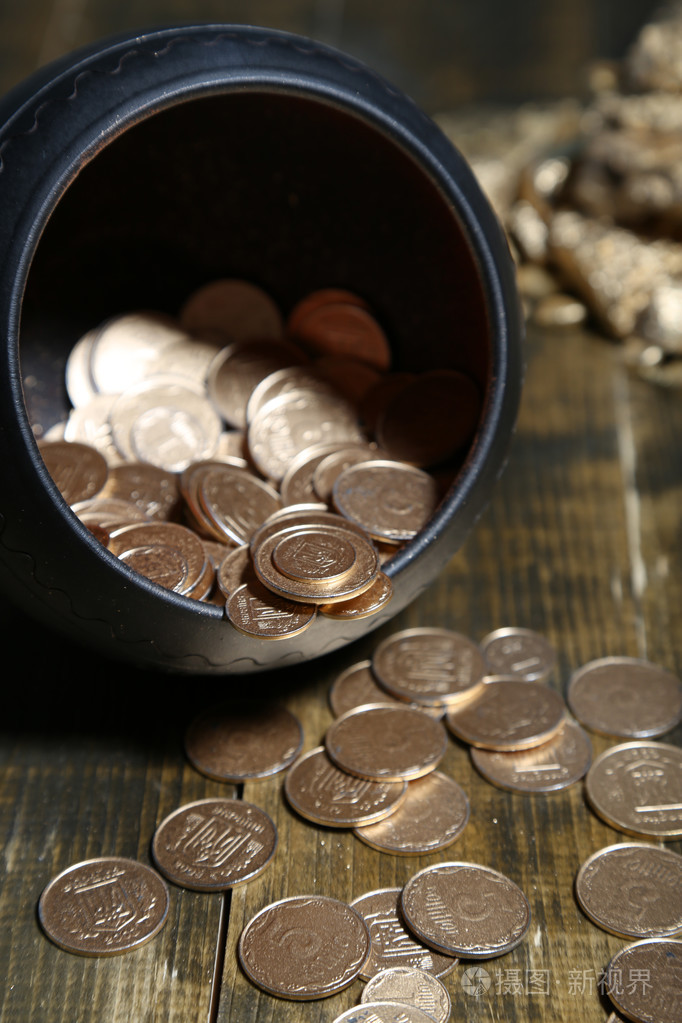 从锅中,木制的背景上掉金币
