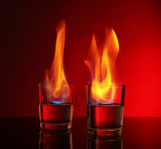 赤背景上燃焼燃烧酒精在红色背景上的眼镜