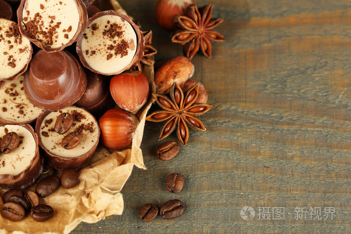 美味的巧克力糖果，与咖啡豆和木制的背景上的螺母