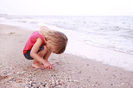 小女孩在海边绘制太阳形在沙子里