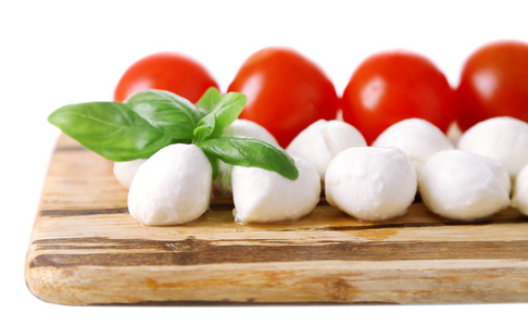 罗勒与红色的番茄的切菜板，孤立的白色衬底上美味的马苏里拉芝士球