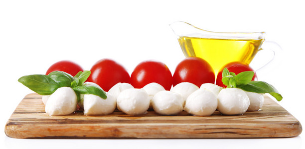 美味的马苏里拉芝士球 罗勒和红色的西红柿 切菜板，孤立的白色衬底上橄榄油组成