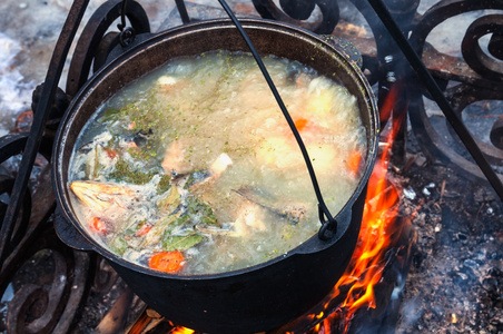 在一个罐在壁炉的烹饪鱼汤。
