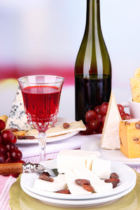 什锦的奶酪板 葡萄与葡萄酒玻璃在桌子上，在明亮的背景上
