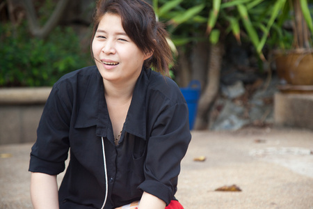 亚洲女性黑衬衫。坐在草坪上