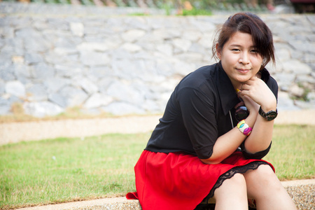 亚洲女性黑衬衫。坐在草坪上