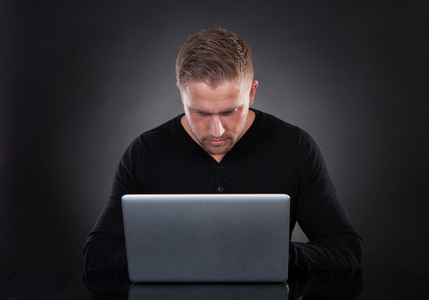男人或黑客夜间在笔记本电脑上工作