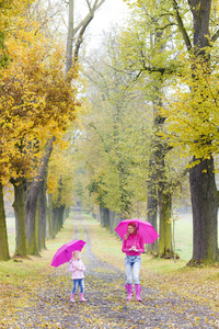 母亲和她的女儿在秋季小巷遮阳伞