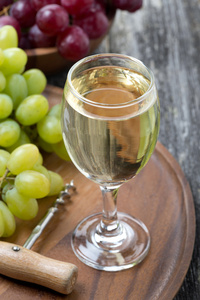 白葡萄酒 开瓶器和葡萄在木板上的玻璃