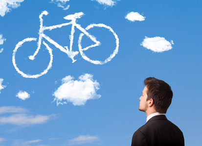 年轻男子低头看自行车在蓝蓝的天空上的云