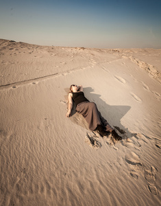 穿着裙子躺在沙漠的沙丘上女人