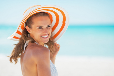 微笑的年轻女士在海滩上的帽子