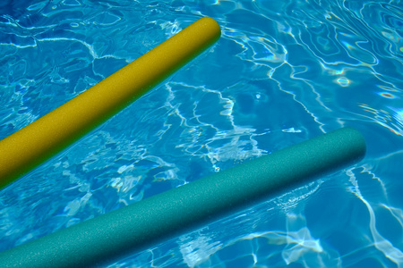 在游泳池里的黄色和蓝色的面条。蓝色的水