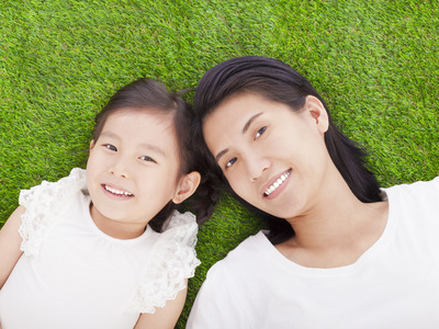 微笑着母亲和女儿躺在草地上