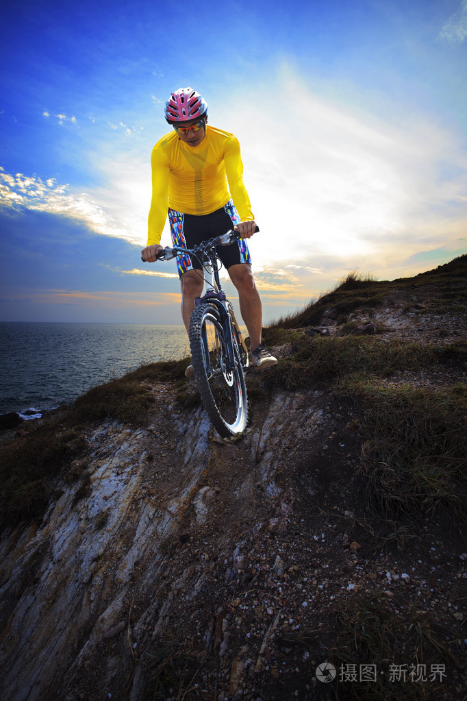 年轻人骑山地自行车山地车土地沙丘昏暗的天空