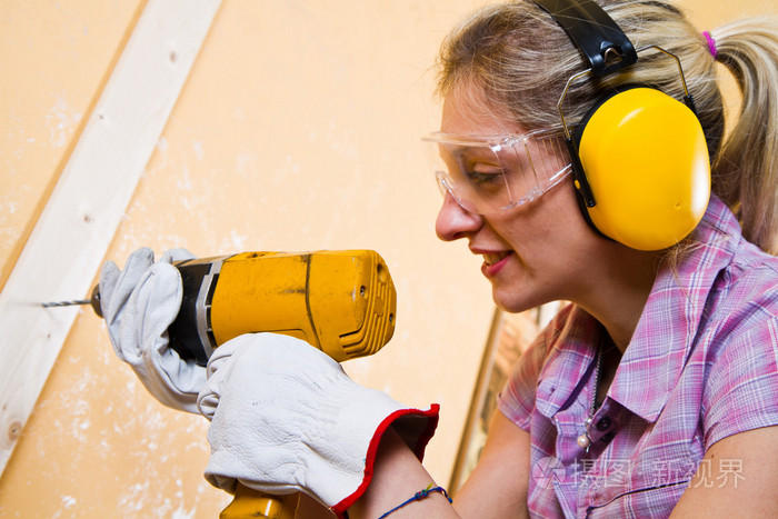 女性的木匠，在工作中使用钻孔机的手