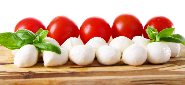 罗勒与红色的番茄的切菜板，孤立的白色衬底上美味的马苏里拉芝士球