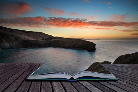 书籍的概念在多岩石的海岸线美丽充满活力的日出