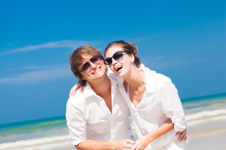 太阳镜中白色的衣服，在户外微笑快乐年轻夫妇的肖像