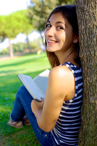 在夏天的公园里可爱的年轻女子看书