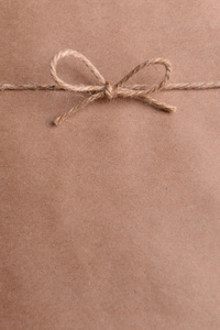 字符串将在蝴蝶结上棕色的纸包装特写