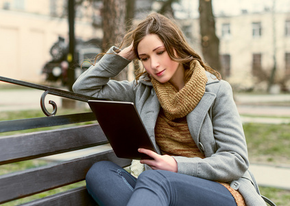 年轻女子坐在平板电脑和阅读