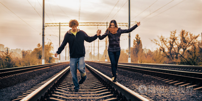 年轻美丽的夫妇在铁路上行走的关系