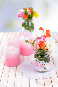 束美丽的鲜艳的花朵放在桌上浅色背景上的罐子里
