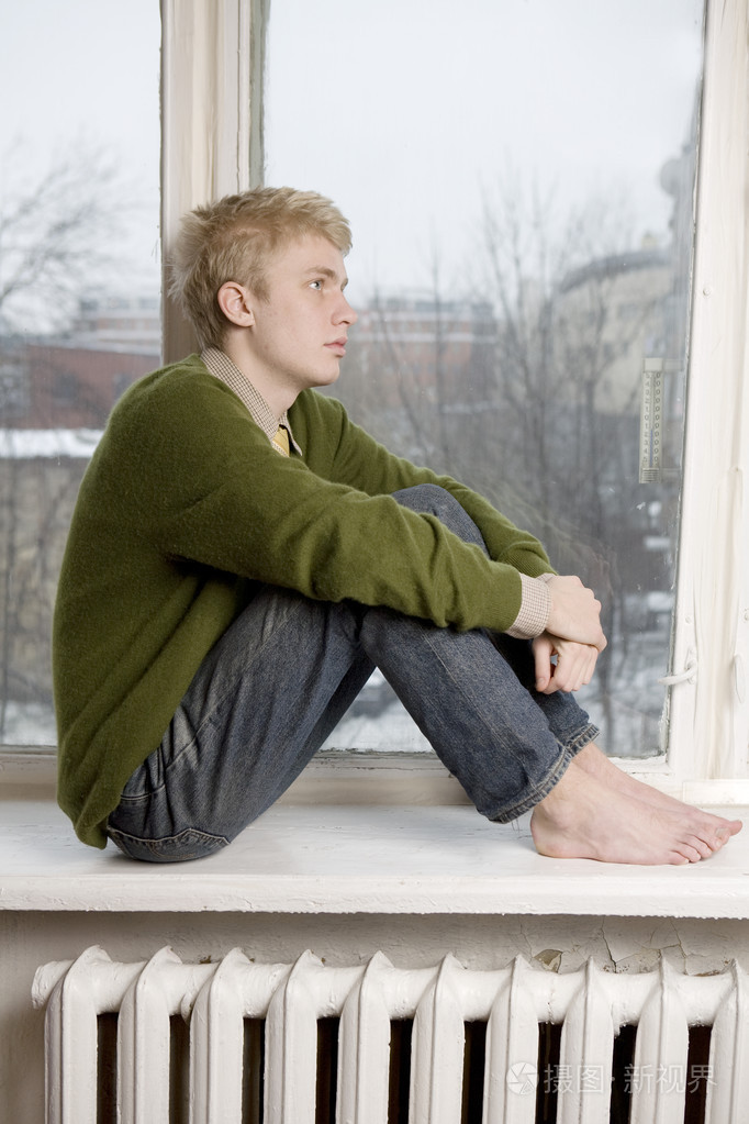 年轻英俊的男人,坐在窗台上