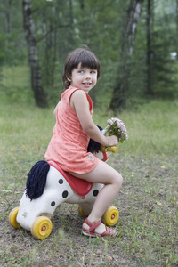 微笑的小女孩骑玩具马