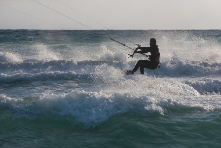 风筝冲浪。kitesurfer 在日落时分破浪前进