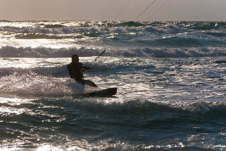 风筝冲浪。kitesurfer 在日落时分破浪前进