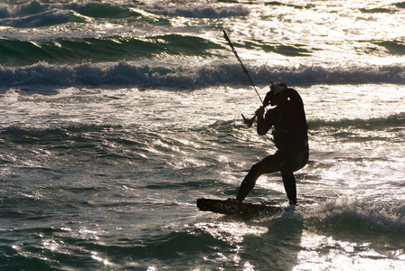 风筝冲浪。kitesurfer 在日落时分破浪前进