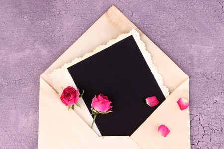 通过空白相纸和美丽的粉红色干的玫瑰木背景上的旧信封