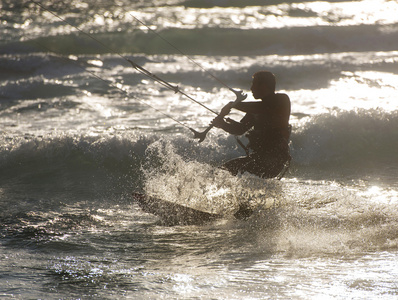 风筝冲浪。kitesurfer 在日落时分破浪前进